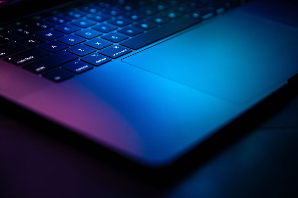 Close-up of a laptop with a blue glow on a dark background
